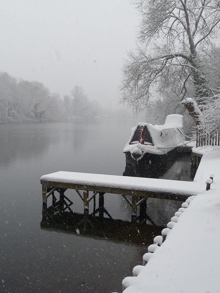 Snowy scene on the banks of the River Thames near Boulters Lock, Maidenhead with jetty and bench